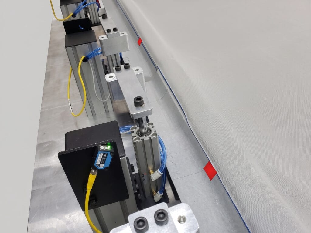 Sensor optorreflectivo y reflectores del poka-yoke en la orilla del nido de verificación