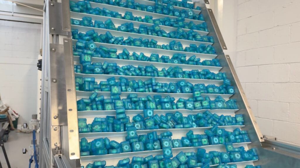 Banda jirafa de alimentación con estuches de hilo dental Oral-B en máquina orientadora de estuches